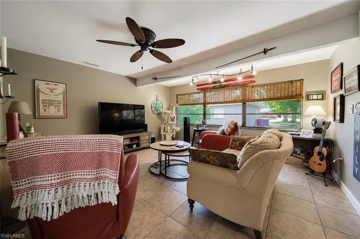 Spacious living area featuring tile flooring, a vaulted ceiling, and a ceiling fan