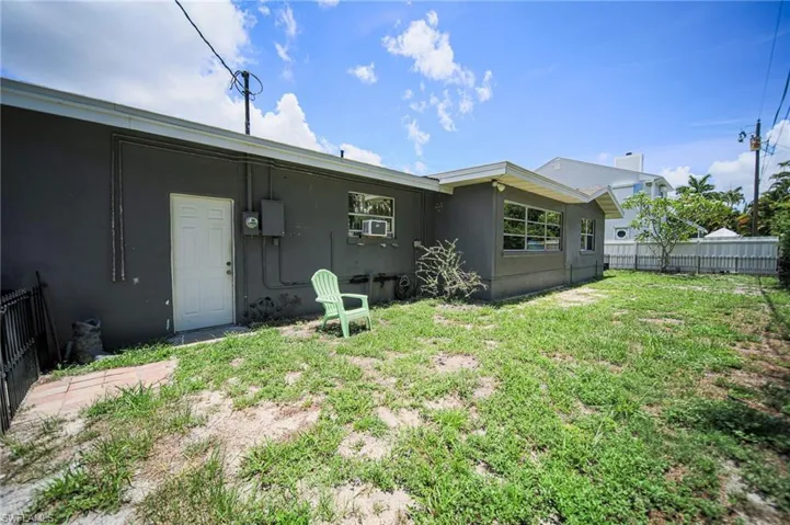 Spacious backyard featuring a stucco exterior, multiple windows, and a white side door