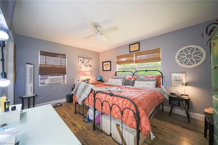 Bedroom featuring wood-finish flooring, two windows with woven blinds, and a ceiling fan