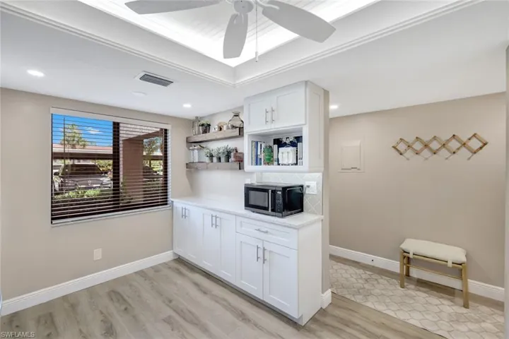 Kitchen featuring light wood-type flooring, white cabinets, backsplash, and ceiling fan