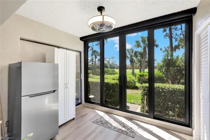 Kitchen featuring a textured ceiling, light hardwood / wood-style floors, stainless steel fridge, and white cabinets
