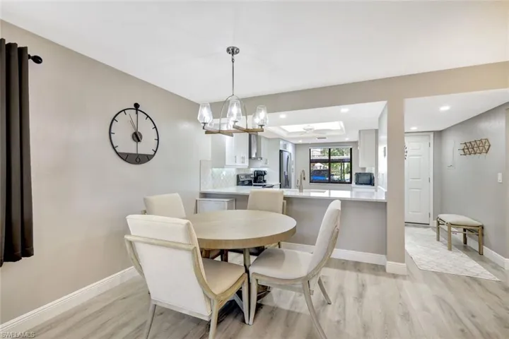 Dining space with sink, light wood-type flooring, and ceiling fan with notable chandelier