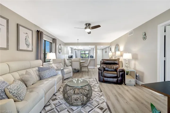 Living room featuring light wood-type flooring and ceiling fan with notable chandelier