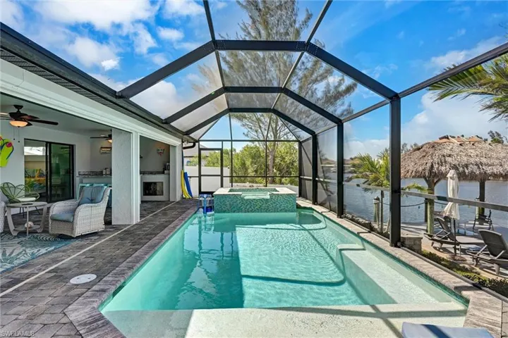 Integrated pool / spa featuring a sunroom, a patio area, glass enclosure, and a water view