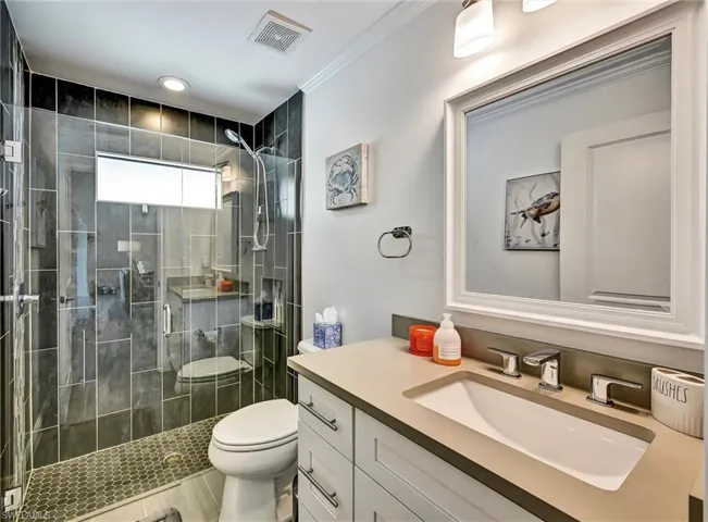 Full bath with vanity, a full-tile shower, and crown molding