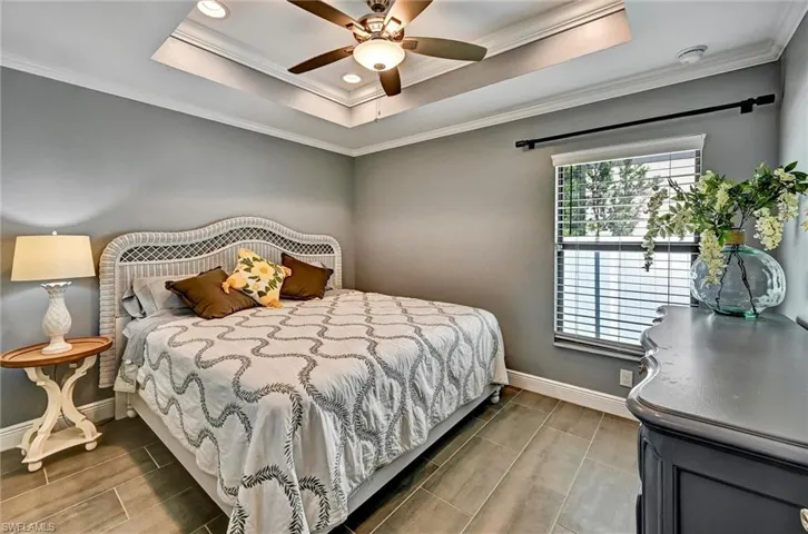 Bedroom with crown molding, a ceiling fan, a tray ceiling, tile floors, and recessed lighting.