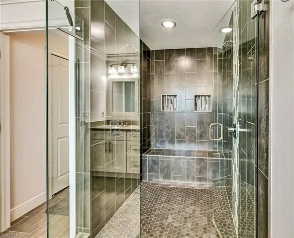 Primary Bathroom with a full tile shower, tile-patterned floor, and a bench seat.