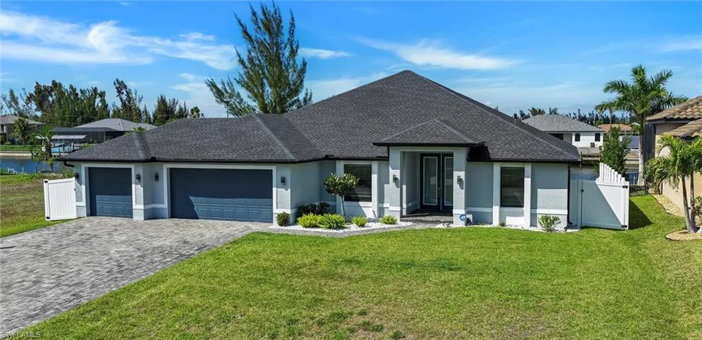 View of front of home with an attached 3-car garage, stucco siding, decorative driveway, and a gate