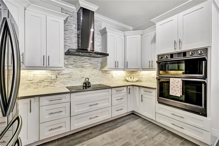 Kitchen featuring stainless steel double oven, fridge, full wall backsplash, 42" white cabinets