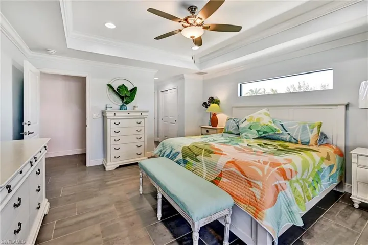 Primary Bedroom with recessed lighting, dual closets, ceiling fan, a tray ceiling, and crown molding, and tile floors