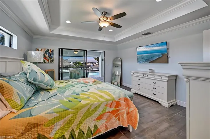 Primary Bedroom with recessed lighting, dual closets, ceiling fan, a tray ceiling, and crown molding, and tile floors