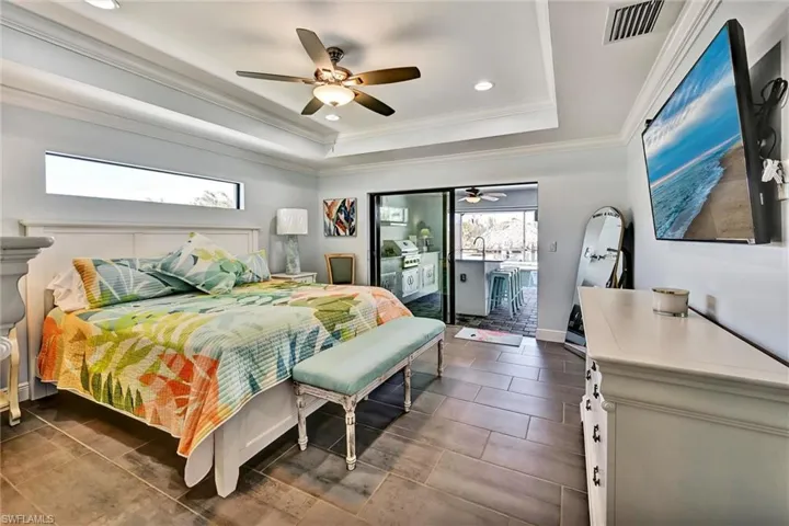Primary Bedroom with recessed lighting, dual closets, ceiling fan, a tray ceiling, and crown molding, and tile floors