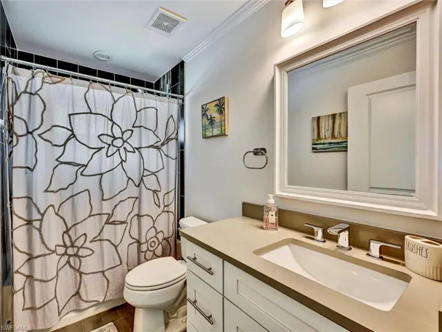 Bathroom with vanity, crown molding, and shower/bath combination