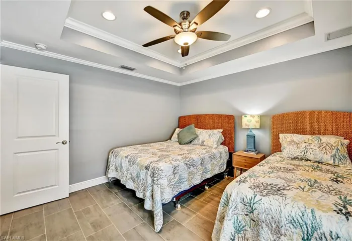 Bedroom with crown molding, a ceiling fan, a tray ceiling, tile floors, and recessed lighting.
