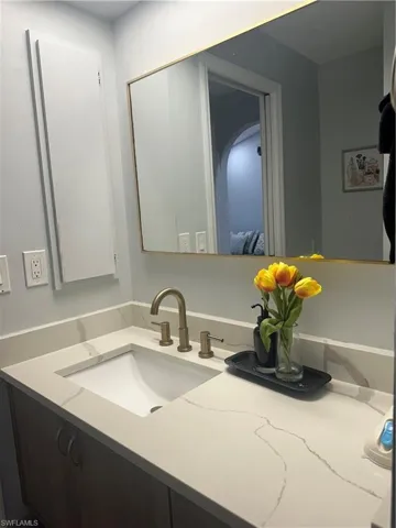 Vanity featuring a rectangular undermount sink, a bronze-finish faucet, and a light-toned countertop with veining