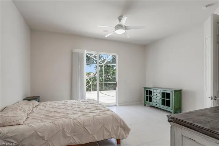 Bedroom with light tile patterned flooring, access to exterior, baseboards, and ceiling fan