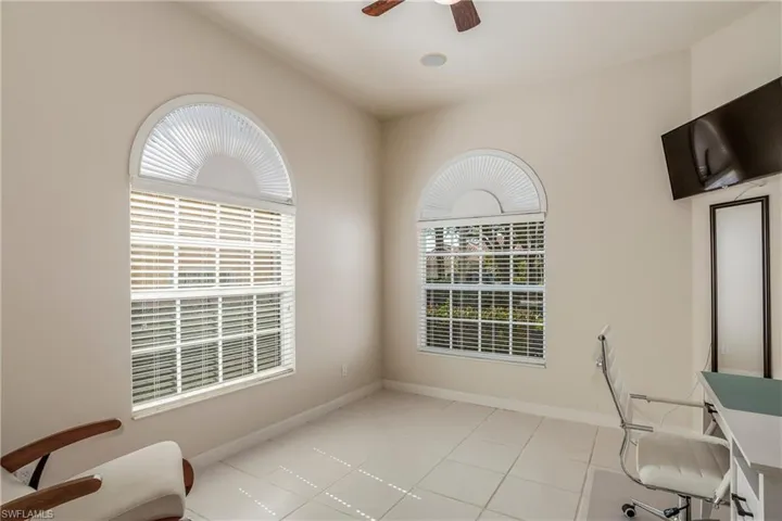 Home office featuring a ceiling fan, light tile patterned floors, and baseboards
