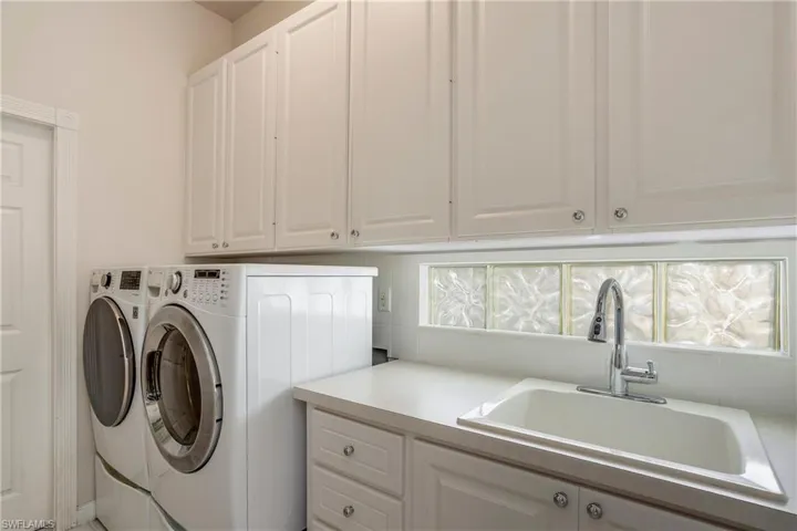 Laundry area with a sink, cabinet space, washing machine and dryer, and plenty of natural light