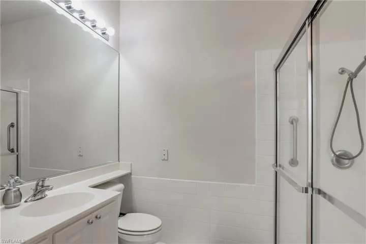 Full bath with vanity, toilet, tiled shower, and tile walls