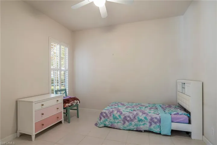 Bedroom featuring baseboards, light tile patterned floors, and a ceiling fan