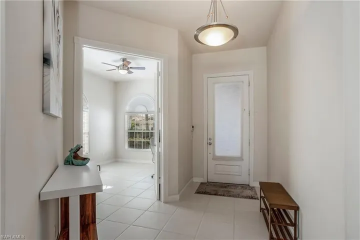 Foyer entrance with a ceiling fan, light tile patterned floors, and baseboards