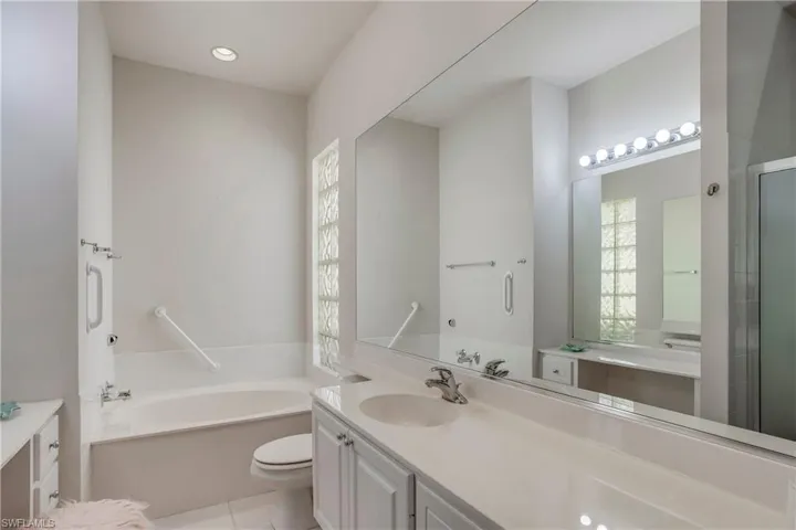 Bathroom with tile patterned flooring, vanity, toilet, a garden tub, and a shower with shower door
