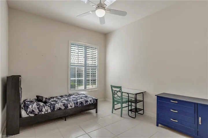 Tiled bedroom featuring a ceiling fan and baseboards