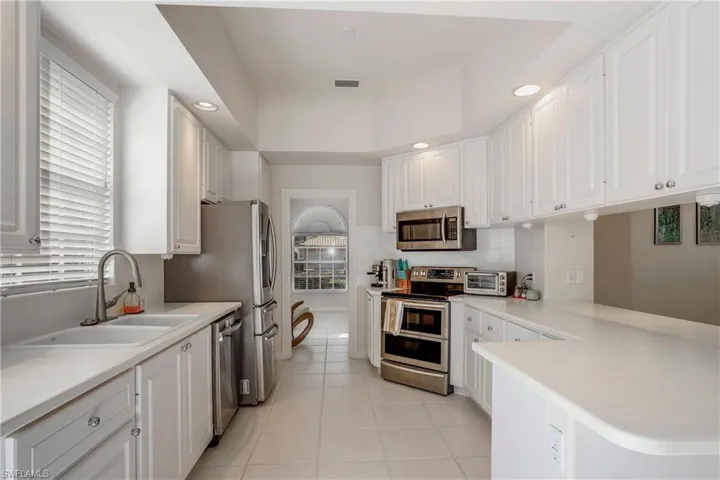 Kitchen with a sink, stainless steel appliances, visible vents, white cabinets, and decorative backsplash