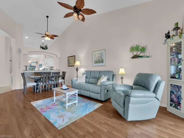 Living room featuring arched walkways, ceiling fan, wood finished floors, and high vaulted ceiling