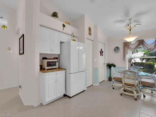 Kitchen with freestanding refrigerator, white cabinetry, and light tile patterned floors
