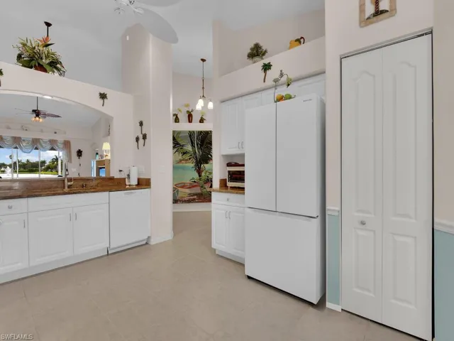 Kitchen with a ceiling fan, white appliances, white cabinets, and decorative light fixtures