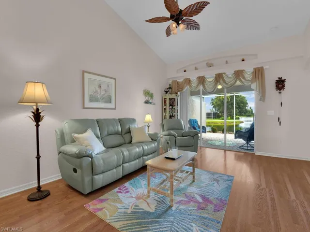 Living area with ceiling fan, wood finished floors, and high vaulted ceiling