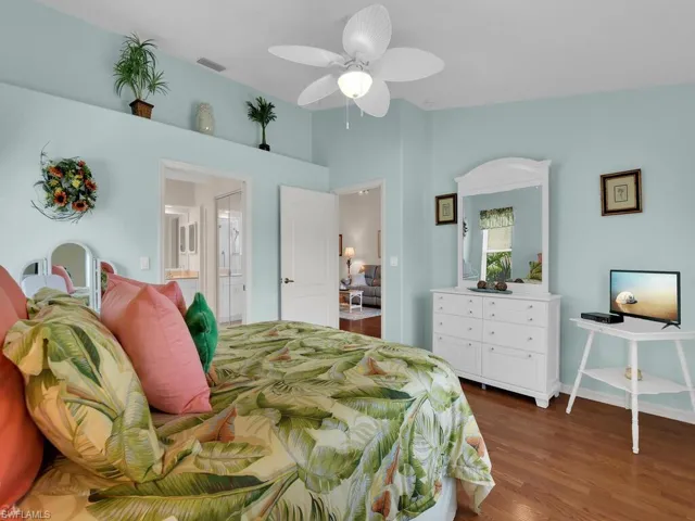 Bedroom featuring wood finished floors, lofted ceiling, ensuite bathroom, and ceiling fan