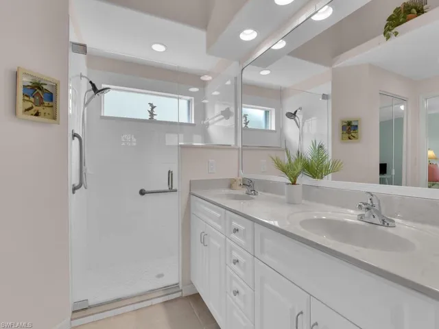 Bathroom featuring a stall shower, double vanity, tile patterned floors, and recessed lighting