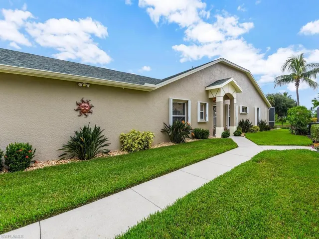 View of front of house featuring stucco siding, a front yard, and a shingled roof