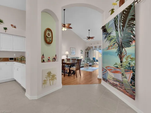 Corridor featuring arched walkways, light tile patterned flooring, and high vaulted ceiling