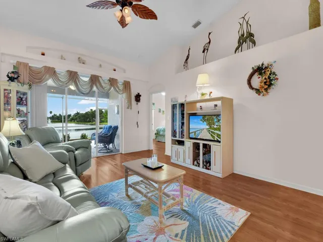 Living area featuring wood finished floors, ceiling fan, and arched walkways