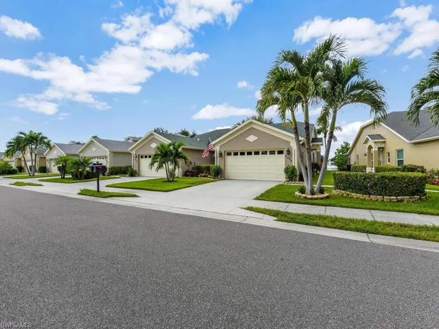 Single story home featuring driveway, a residential view, a garage, stucco siding, and a front yard