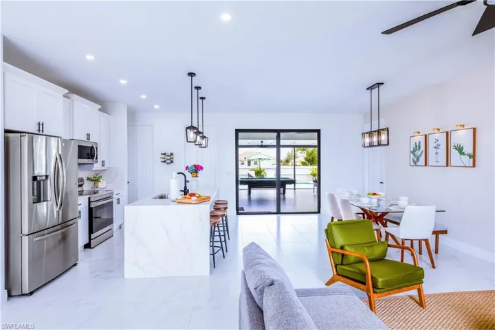 Kitchen featuring appliances with stainless steel finishes, white cabinets, recessed lighting, decorative light fixtures, and light stone counters