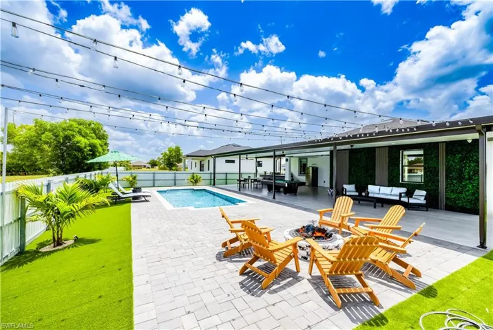 View of pool featuring a fenced backyard and an outdoor living space with a fire pit