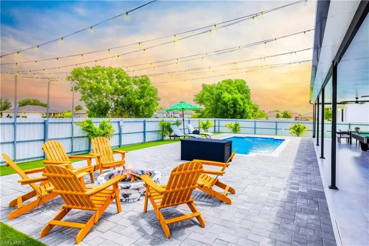 Pool at dusk featuring a fire pit, a patio, and a fenced backyard
