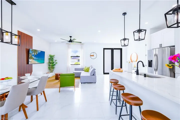 Kitchen with hanging light fixtures, light stone countertops, stainless steel refrigerator with ice dispenser, and recessed lighting