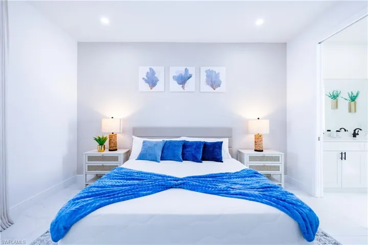 Bedroom with connected bathroom, recessed lighting, and light marble finish flooring