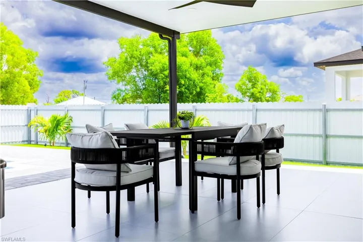 Fenced backyard featuring outdoor dining area, a patio area, and a ceiling fan