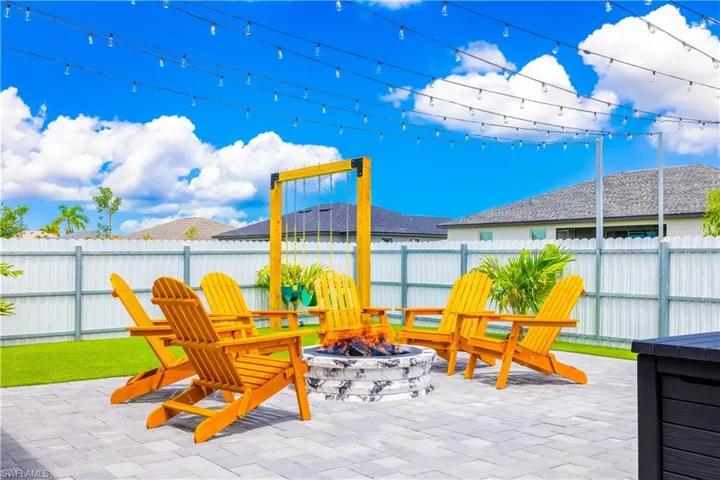 View of playground featuring a fenced backyard, a fire pit, and a patio area