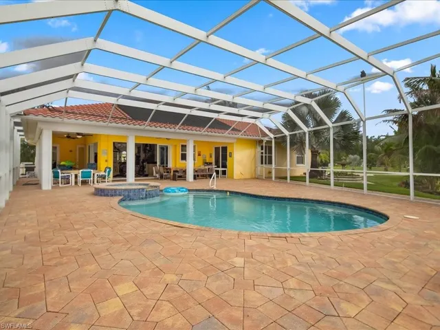 View of pool with a pool with connected hot tub, a patio area, a lanai, outdoor dining area, and a sunroom