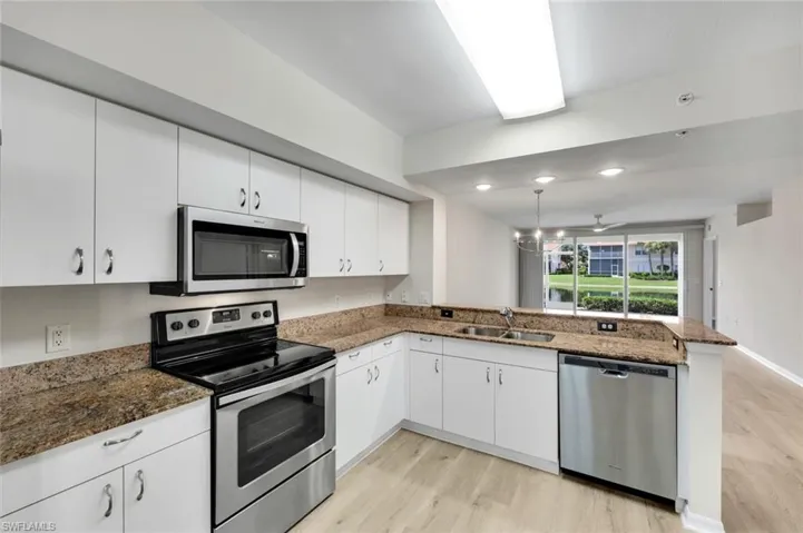 Kitchen featuring appliances with stainless steel finishes, light wood finished floors, white cabinetry, decorative light fixtures, and recessed lighting