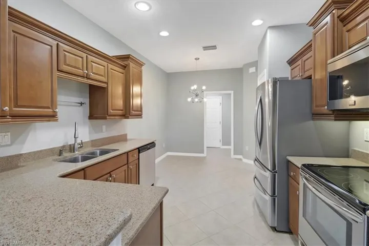 Kitchen featuring light tile patterned flooring, a chandelier, stainless steel appliances, pendant lighting, and sink