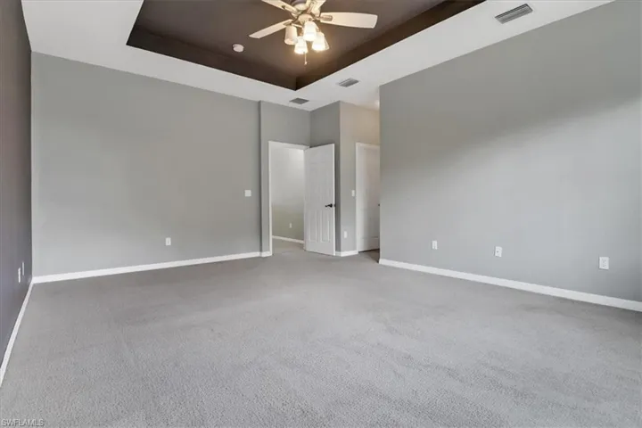 Carpeted spare room with a raised ceiling and ceiling fan