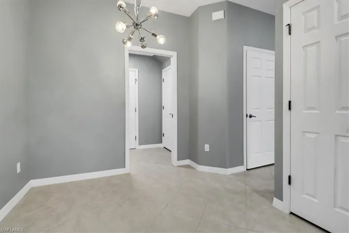Tiled spare room featuring a chandelier